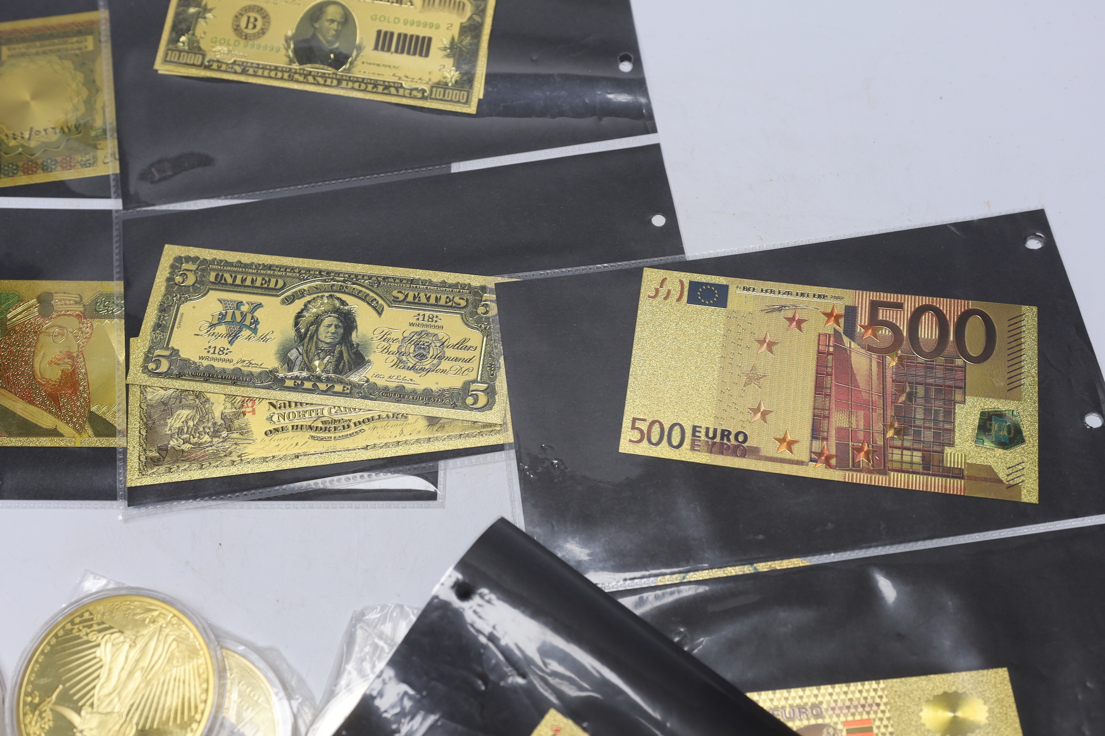 A collection of gold plated medallions and bank notes